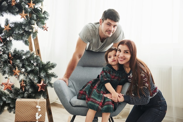 Vacanze insieme. Ritratto della famiglia felice sulla celebrazione del nuovo anno. La ragazza si siede sulla sedia.