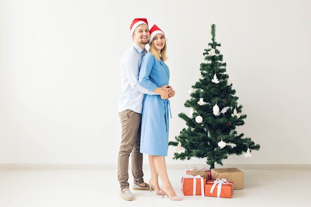 Vacanze invernali e concetto di famiglia - Giovani coppie felici vicino all'albero di Natale a casa.