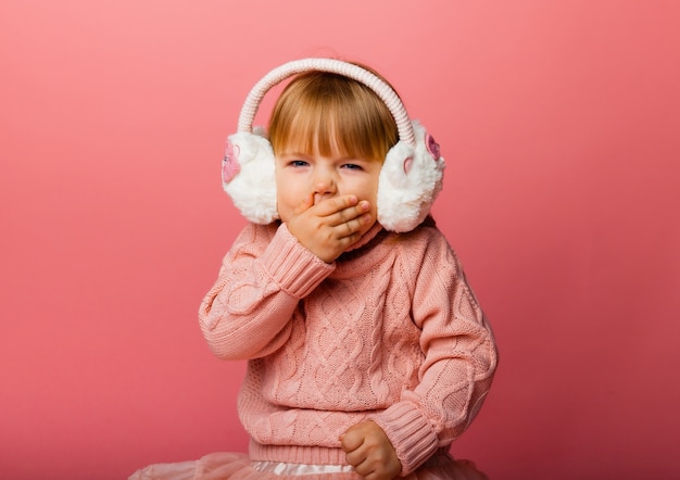 Vacanze invernali. La bambina ascolta musica in cuffie invernali. Ragazza in abiti invernali.