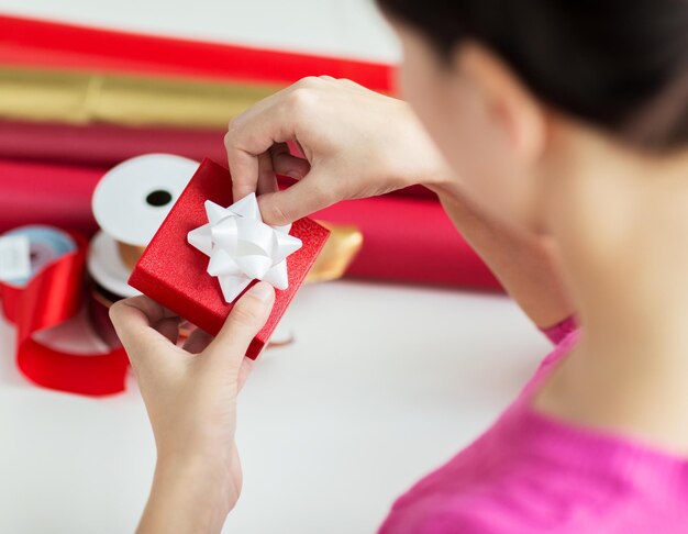 Vacanze, persone e concetto di celebrazione - primo piano di una donna che decora il regalo di Natale