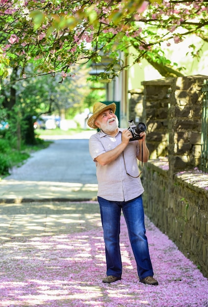 Vacanze primaverili Godersi il tempo libero Passeggiando per la sua strada preferita Viaggi e turismo Fotografo in giardino Catturare la bellezza primaverile Senior man tenere la fotocamera Primavera sakura bloom Concetto naturalista