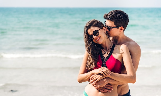 Vacanze romantiche amanti giovani coppie felici abbraccio e in piedi sulla sabbia in mare divertendosi e rilassarsi insieme sulla spiaggia tropicale. Vacanze estive