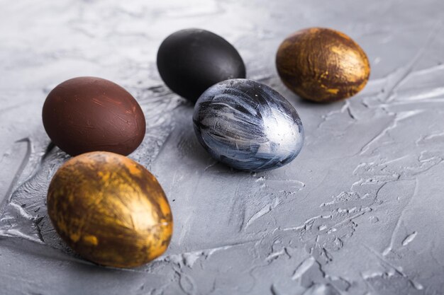 Vacanze, tradizioni e concetto di Pasqua - Uova di Pasqua eleganti scure su sfondo grigio.