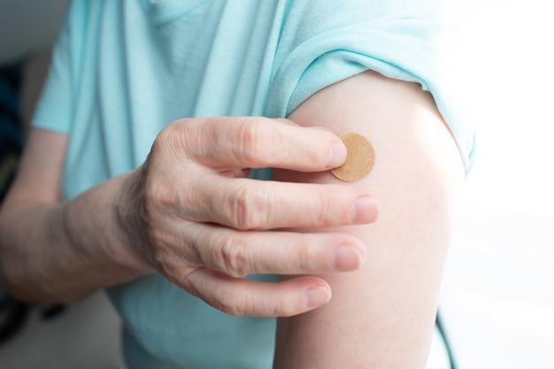 Vaccinazione donna anziana in studio medico con cerotto adesivo per vaccino covid-19.