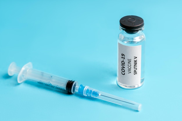 Vaccinazione russa Sputnik V e iniezione di siringa contro il vaccino contro il coronavirus sullo sfondo blu
