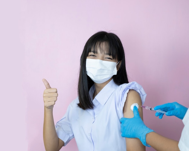 Vaccinazione studentesca asiatica su sfondo rosa.