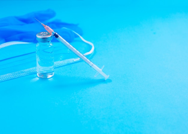 Vaccini e siringhe maschera facciale su sfondo blu