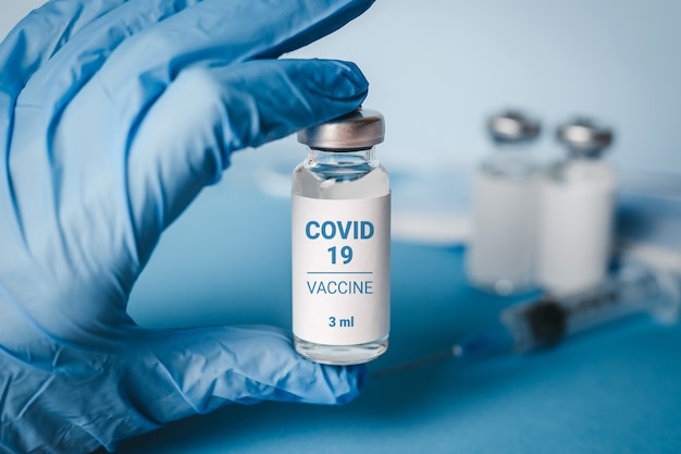 Vaccino contro il coronavirus. Mano del medico in un tubo porta guanti medico con vaccino Coronavirus per il virus COVID 2019-nCoV. Concetto di coronavirus 2019. Nuovo ceppo