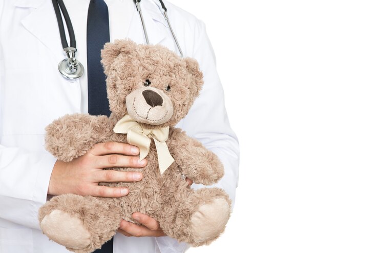 Vale la tua fiducia. Ritagliata colpo di un medico maschio che tiene un orsacchiotto