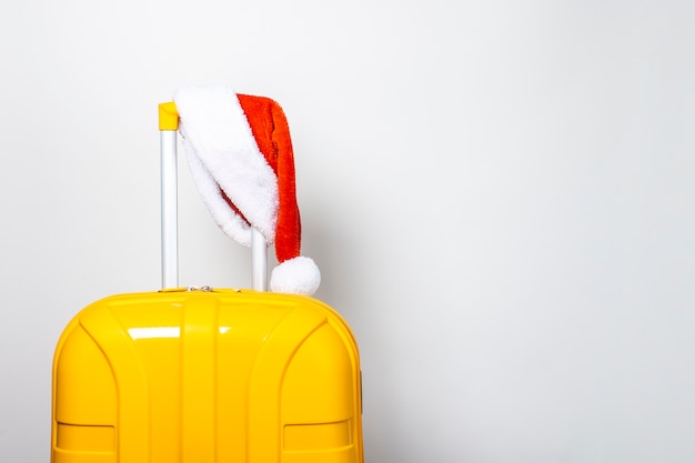 Valigia di plastica gialla che indossa un cappello rosso di Babbo Natale