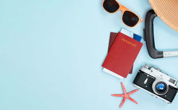 Valigia, passaporto, biglietti, occhiali da sole, cappello per il sole e stelle marine su sfondo azzurro. concetto di viaggio