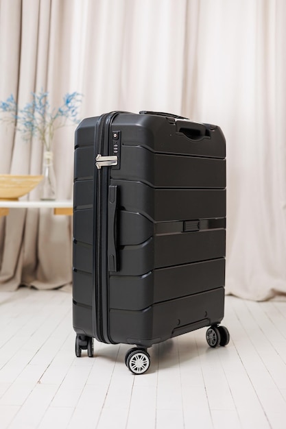 Valigia robusta in plastica nera per il trasporto di bagagli su sfondo bianco Una valigia luminosa per il viaggio