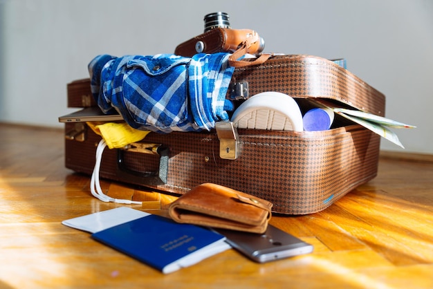 Valigia sovraccarica di vestiti. concetto di viaggio. borsa con indumento. passaporto biometrico davanti