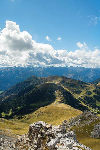 Valle soleggiata tra maestose colline verdi e nuvolose di montagna ricoperte di erba e cespugli verdi e lussureggianti