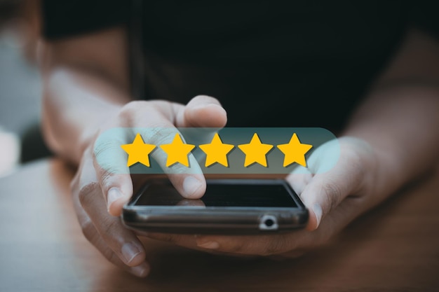 Valutazione e feedback delle recensioni 5 stelle il migliore e l'eccellente ammirazione del recensore da vicino sulla mano del cliente premendo sullo schermo dello smartphone con cinque stelle dorate