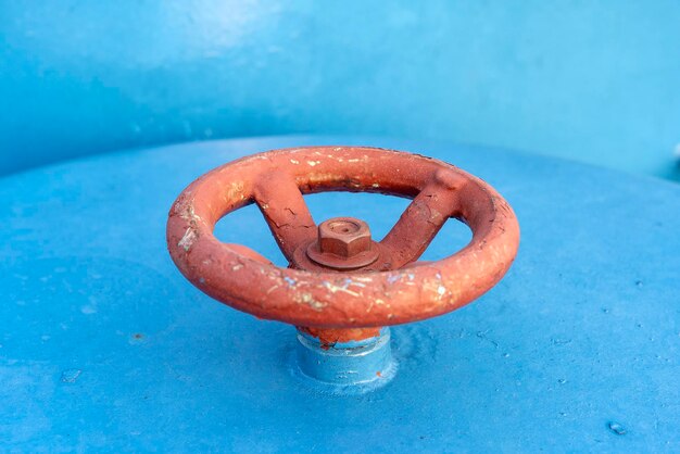 Valvola rossa sul tubo blu Valvola con maniglia della ruota Ingranaggio industriale Primo piano