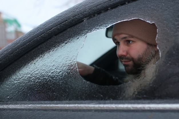 Vandalismo inverno uomo ha rotto il vetro dell'auto un sassolino