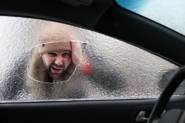 Vandalismo inverno uomo ha rotto il vetro dell'auto un sassolino