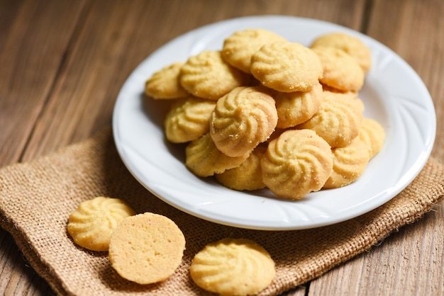 Vaniglia dei biscotti della colazione sulla zolla bianca e sui biscotti di legno e mini biscotti