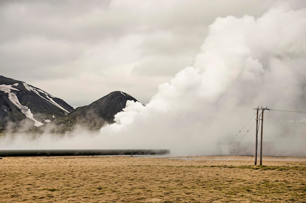 Vapore caldo che esce dal suolo in un paesaggio erboso con linee elettriche vicino alla centrale elettrica