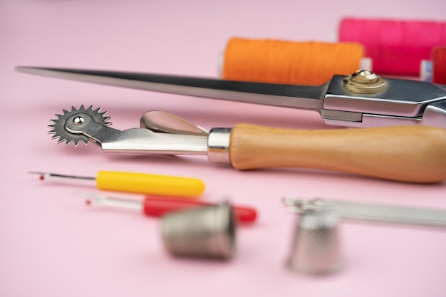 vari accessori e strumenti su misura per la sartoria su sfondo rosa