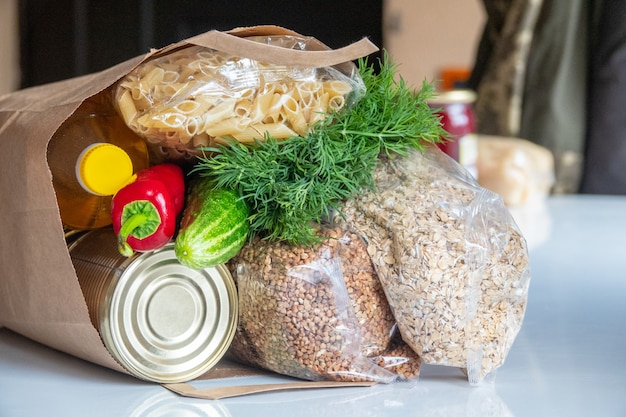 Vari cibi in scatola, pasta e cereali in una scatola di cartone. Donazioni di cibo o concetto di consegna di cibo.