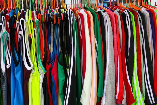 Vari di sport abbigliamento casual camicie maglia pantaloncini appesi su una cremagliera in un mercato delle pulci al dettaglio e commercio all'ingrosso display concept