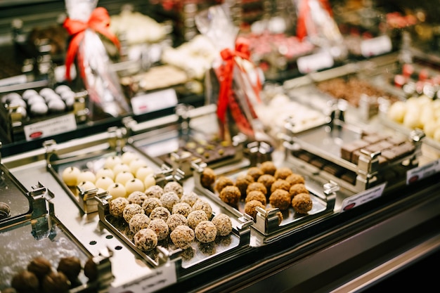 Vari dolci rotondi al cioccolato su vassoi in una vetrina di pasticceria