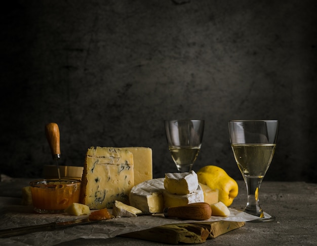 Vari formaggi, vino in bicchieri e mele cotogne