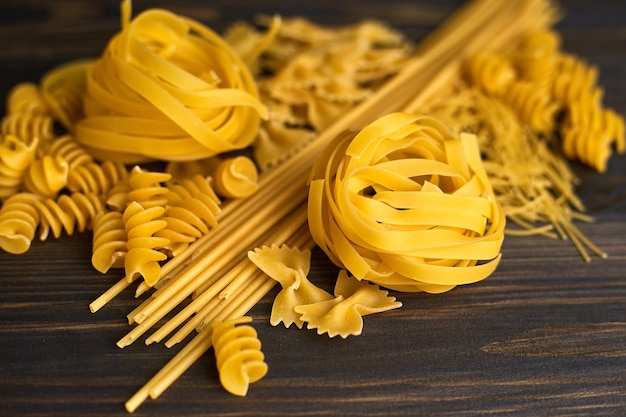 Vari mix di pasta sulla tavola di legno scuro. cibo italiano