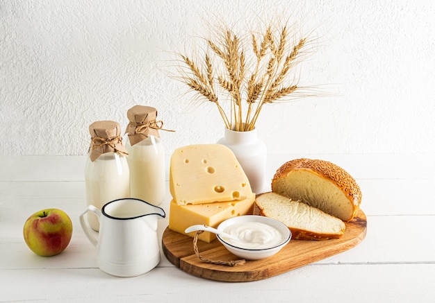 Vari prodotti lattiero-caseari mele e un vaso con un mazzo di orecchie su sfondo bianco vista frontale il concetto della festa ebraica di Shavuot