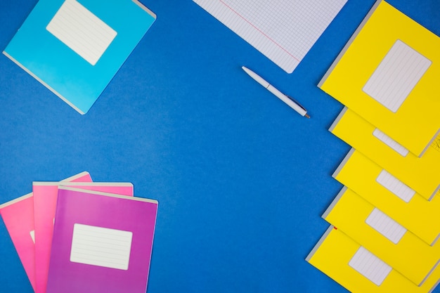 vari quaderni di scuola colorati su blu