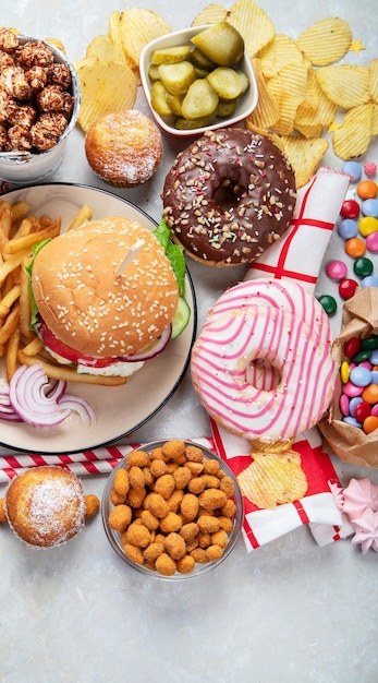 Vari tipi di cibo americano patatine fritte hamburger nuggets hotdog chips salse di popcorn su uno sfondo bianco vista dall'alto