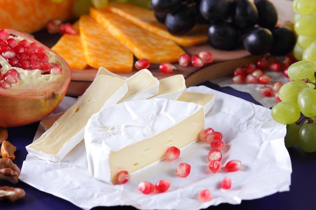 Vari tipi di composizione di formaggio su uno sfondo blu closeup Formaggi assortiti frutta e noci su una tavola di legno