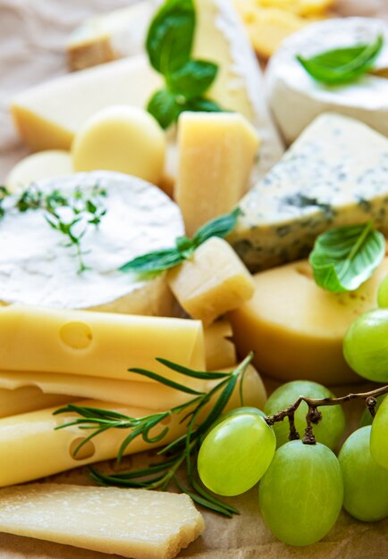 Vari tipi di formaggio, basilico e uva su un tavolo