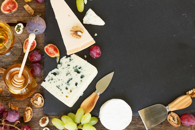 Vari tipi di formaggio sul tagliere nero con copia spazio