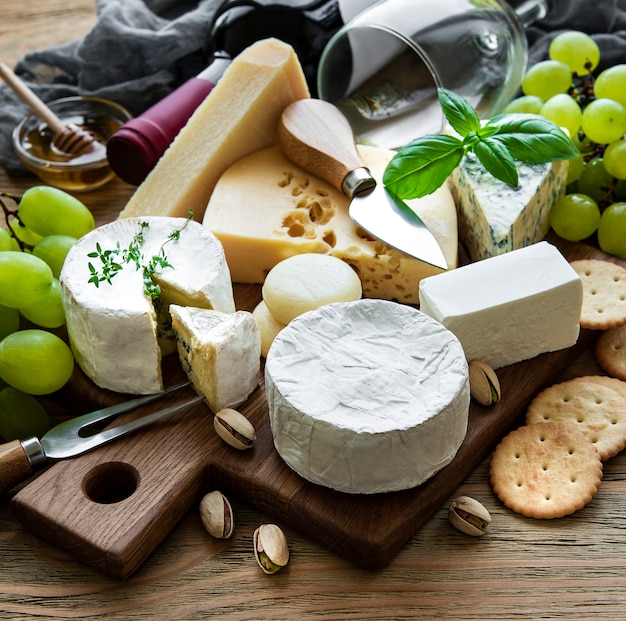 Vari tipi di formaggio, uva e vino su un tavolo di legno