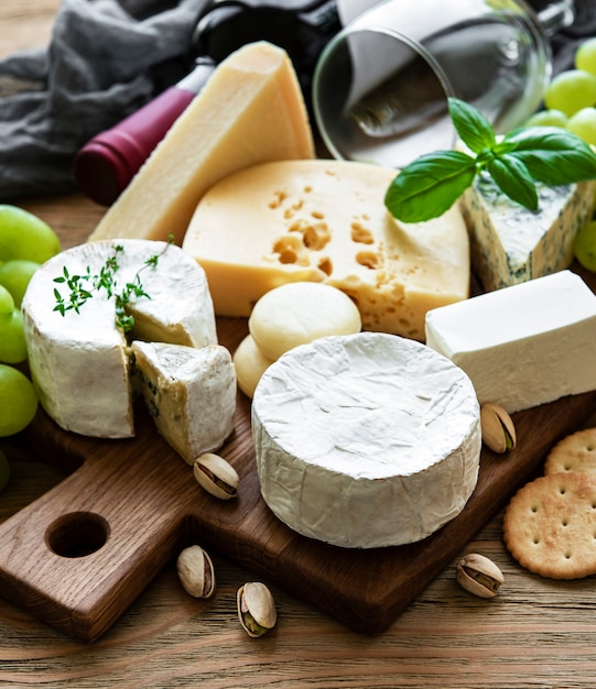 Vari tipi di formaggio, uva e vino su un tavolo di legno