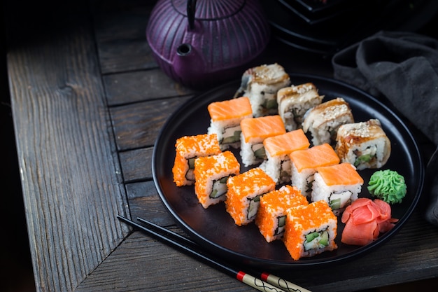 Vari tipi di rotoli di sushi serviti sulla banda nera nel buio