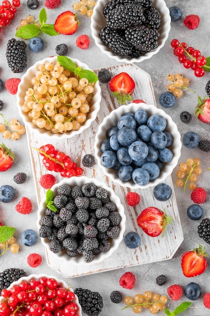 Varie bacche fresche in ciotole su sfondo grigio di cemento Concetto di cibo sano