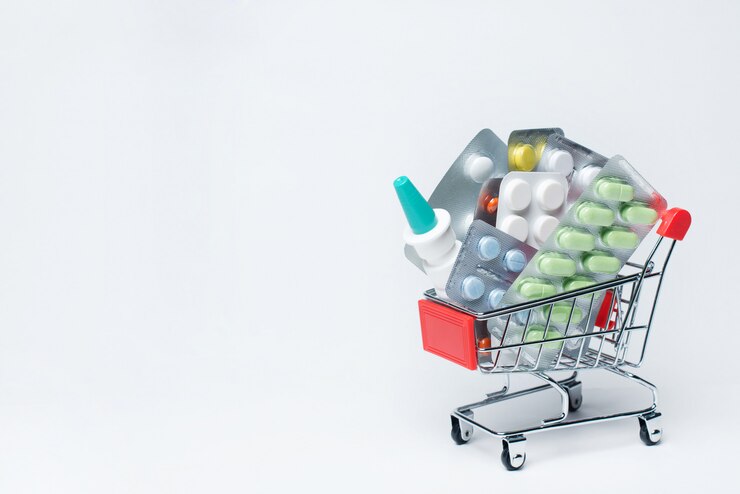 Varie capsule, compresse e medicinali nel carrello del negozio su una superficie blu