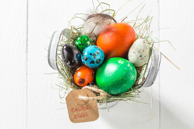 Varie uova per Pasqua nel secchio con fieno