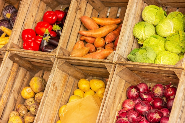 Varie verdure in scatole di legno sul bancone del mercato cibo biologico sano e vegetariano