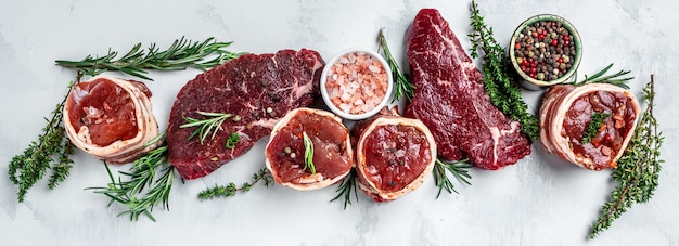 Varietà di bistecche di carne di prima scelta di black angus crudo, bistecca di manzo, filetto di filetto mignon o grigliate con condimento su uno sfondo chiaro. banner, vista dall'alto della ricetta del menu.