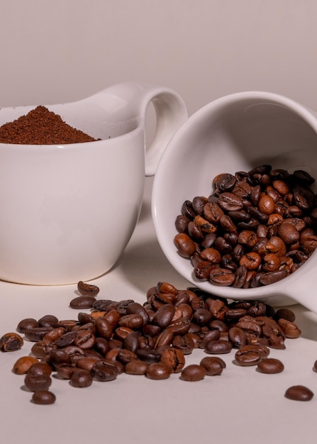 Varietà di caffè Due tazze di porcellana bianca con chicchi di caffè e caffè macinato