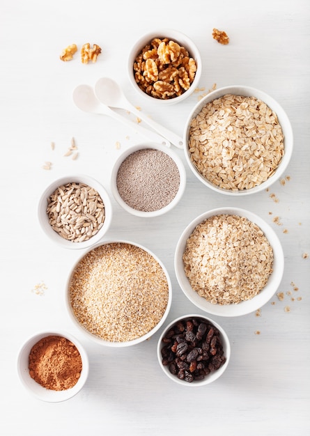 Varietà di cereali e noci crudi per la colazione. Fiocchi di avena e acciaio tagliati, orzo, noce, chia, uvetta. Ingredienti sani