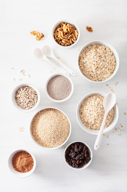 Varietà di cereali e noci crudi per la colazione. Fiocchi di avena e acciaio tagliati, orzo, noce, chia, uvetta. Ingredienti sani