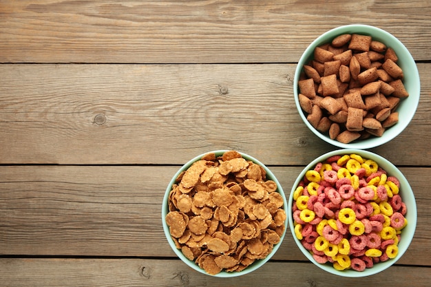 Varietà di cereali in ciotole blu, colazione veloce su fondo di legno grigio. Foto verticale