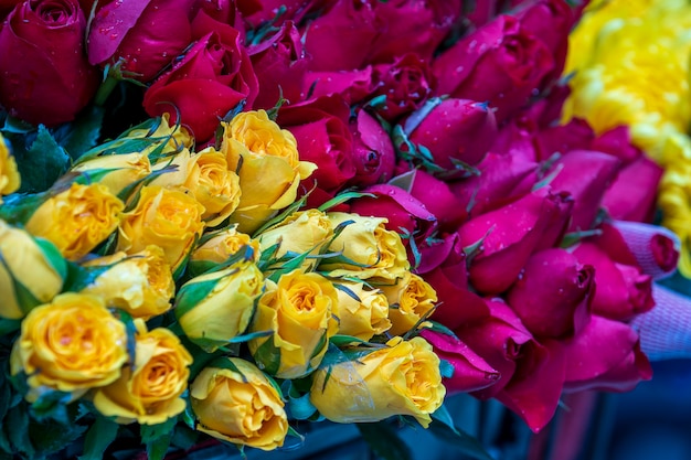 Varietà di fiori rosa colorati avvolti in mazzi per la vendita al mercato di strada