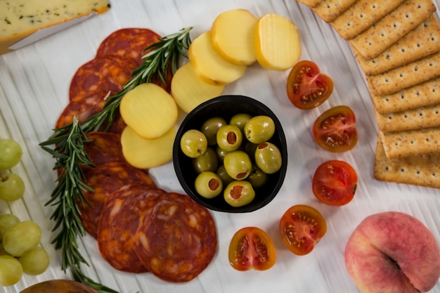 Varietà di formaggi con uva, olive, salame e crackers